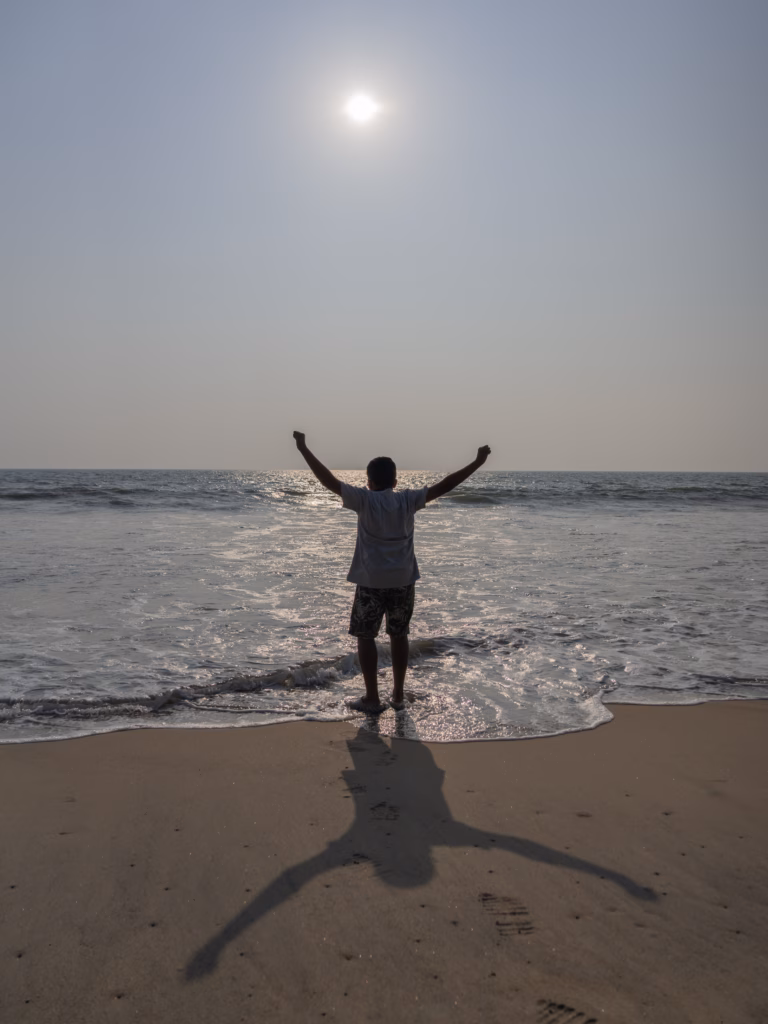 A boy on a beach against the setting sun 